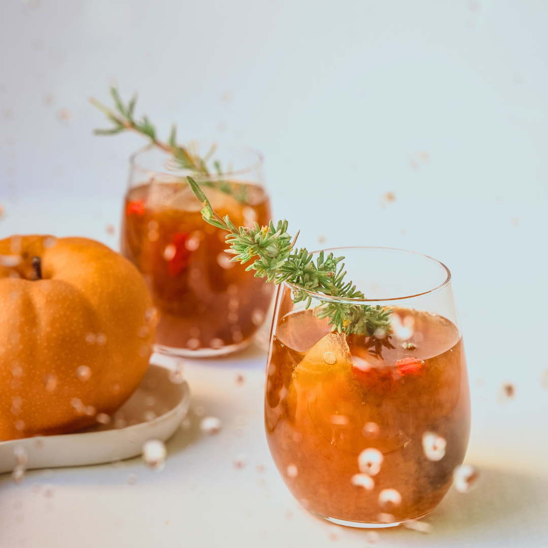 Two glasses of crystal pear with garnishes on a light background