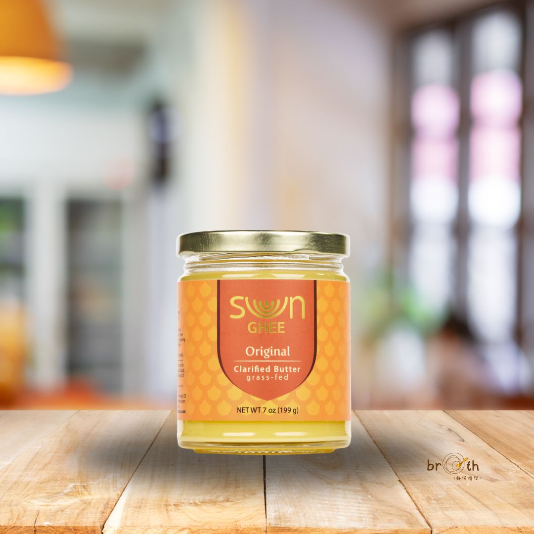 A single jar of Sun Ghee – Pure Original clarified butter displayed on a wooden counter with a blurred kitchen background, emphasizing its premium quality and homey appeal.