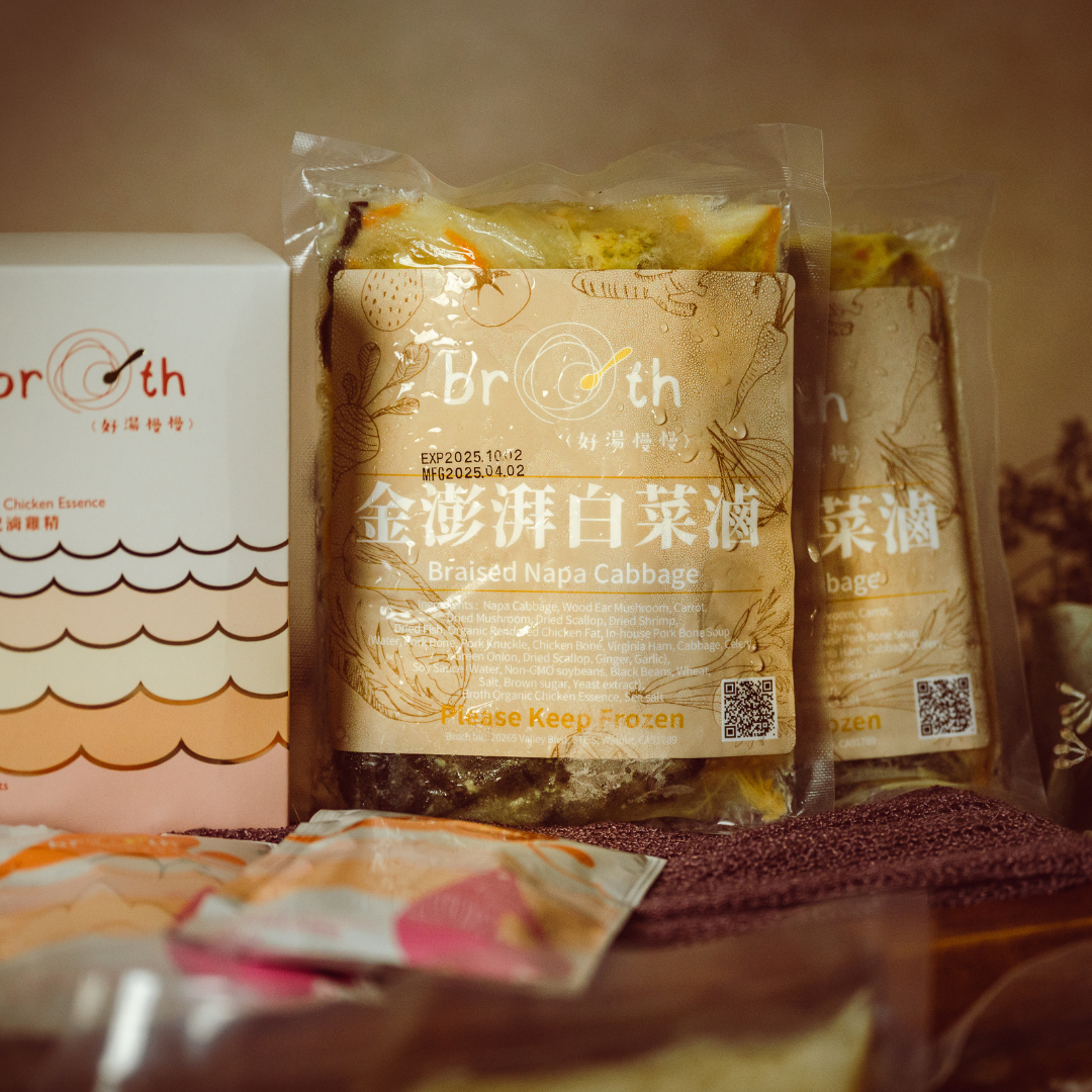 Packages of braised napa cabbage & Goji Jujube Chicken Essence with Broth branding on a wooden surface.
