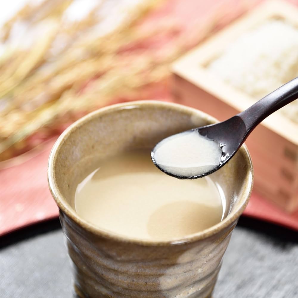 Cup of creamy Yumepirika Amazake with a spoonful being lifted, placed on a textured surface.