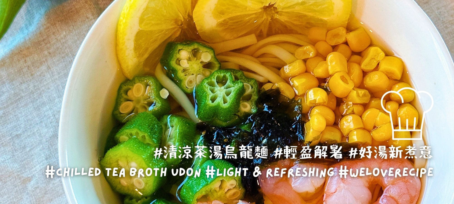 Bowl of chilled tea broth udon topped with sliced okra, sweet corn, shrimp, seaweed, and lemon wedges, creating a light and refreshing summer noodle dish.