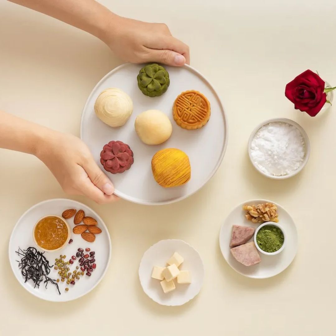 Assorted mooncakes on a plate with ingredients on small plates on a light background
