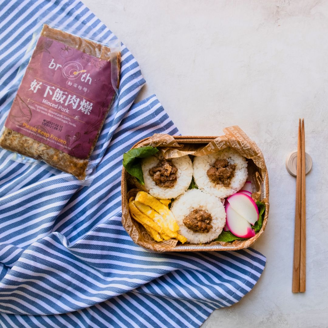 Bento box with a package of Braised Minced Pork on a striped cloth