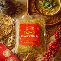 A frozen pack of 【Limited Edition】Royal Golden Crab Soup displayed beside a freshly prepared bowl of crab soup, styled with Chinese New Year decorations, calligraphy scroll, and festive accents.