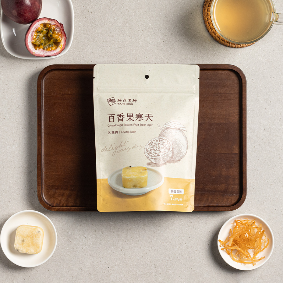 Packaged passion fruit agar on a wooden tray with tea and fruit on a light gray background