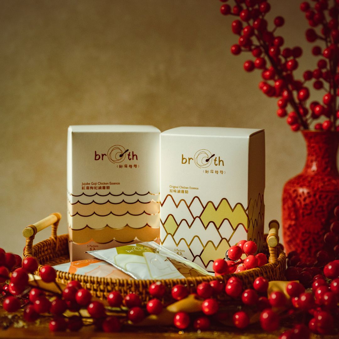 Two Broth (好湯慢慢) chicken essence (Left: Goji Jujube; Right: Original) displayed with individual sachets in a woven tray, styled with red berries and holiday décor.