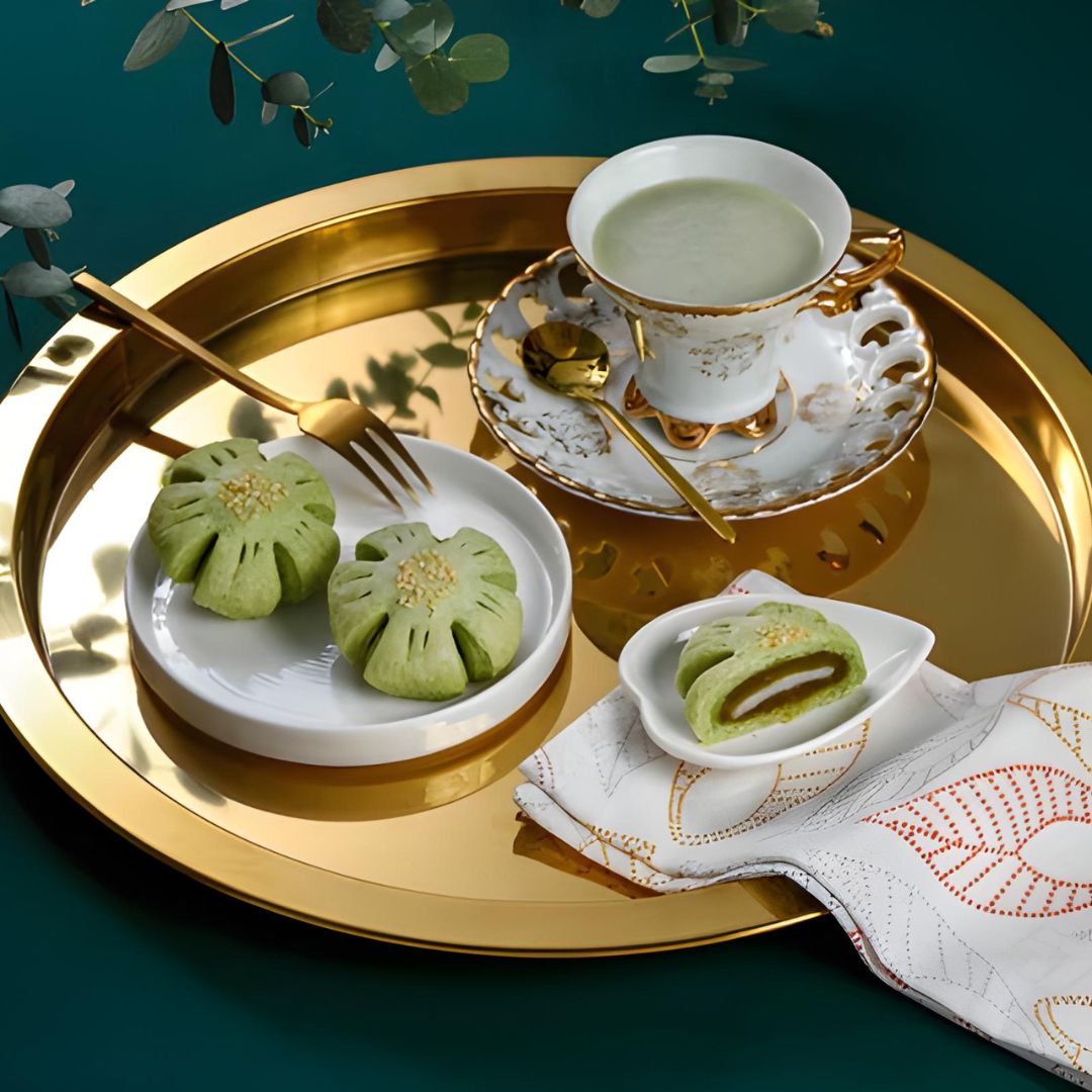 Tea set with green tea and traditional Chinese pastries on a gold tray.