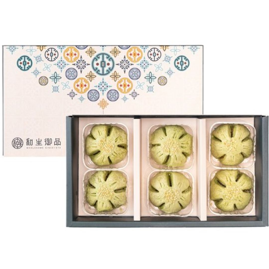 Box of green floral cookies with decorative box on a white background