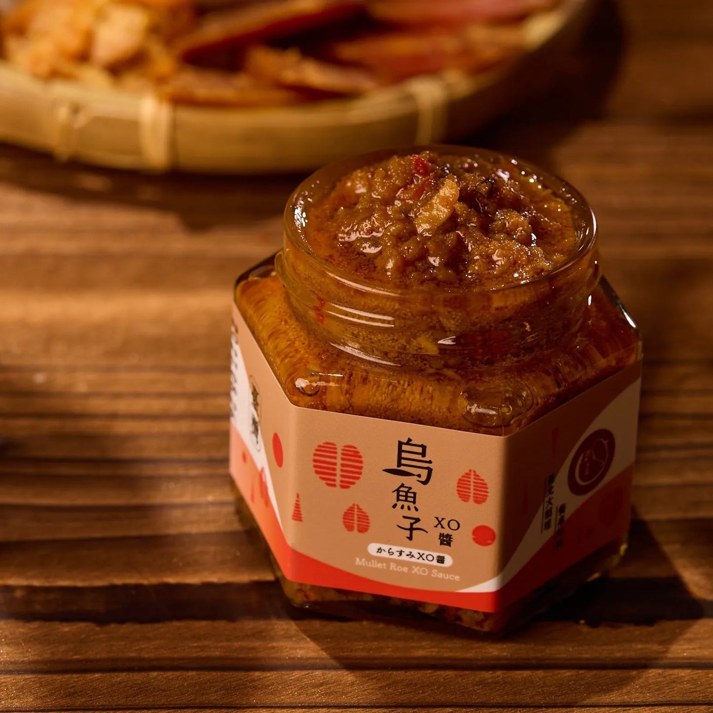 An open jar of 【The Carp】Mullet Roe XO Sauce showing its rich, chunky texture, styled on a wooden table with warm lighting and dried seafood in the background.