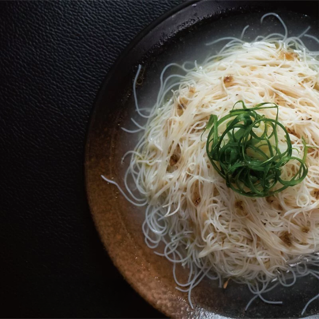Yin Chuan organic Rice Noodle with green onion on a dark plate